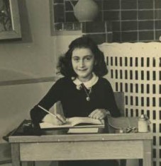 Anne Frank sitting at school desk.
