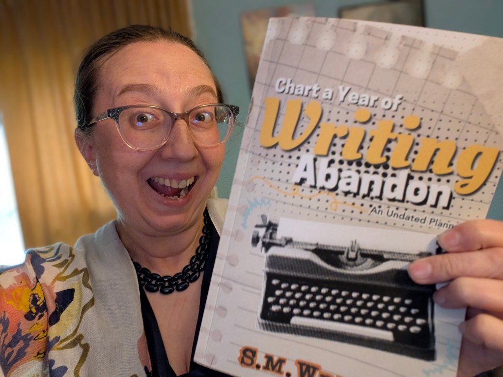 S.M. Wright holding a copy of "Chart a Year of Writing Abandon"